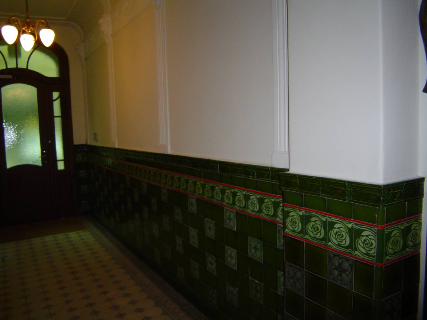 X In Berlin Friedrichshain hat die Malerfirma Restaurierung und Gestaltung exklusive Malerarbeiten das Jugendstil – Treppenhaus incl. Deckenmalerei und Marmormalerei neu Rekonstruiert. Im Eingangsbereich wurde das komplette rechte Fliesenpaneel rekonstruiert. Dabei wurden die Fliesen nachgegossen und in einer speziellen Technik so lasiert, dass diese ihrem gegenüber, auf der linken Seite vorhandenen Bestandsfliesen beeindruckend ähneln. Dabei kommt dem Unternehmen zugute, dass sich in der Firma Restaurierung und Gestaltung mit Norbert Schimpf ein bekannter Malermeister und Restaurator mit historischen und dekorativen Anstrichen beschäftigt, der solche Herausforderungen annimmt. Die beschäftigten Maler im Unternehmen haben dafür und für die Vor- und Malerarbeiten im Treppenhaus alle nötigen vorarbeiten aus einer Hand ausgeführt. Im Treppenhaus selber wurde eine sehr helle Marmorimitation am Paneel angebracht. Alle Holzbauteile wurden mit einer Holzimitation ausgeführt.